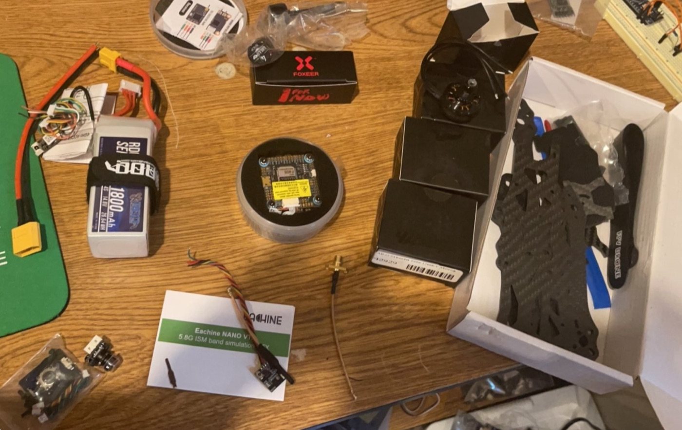 FPV drone frame, battery, flight controller, video transmitter, receiver, and wiring before assembly